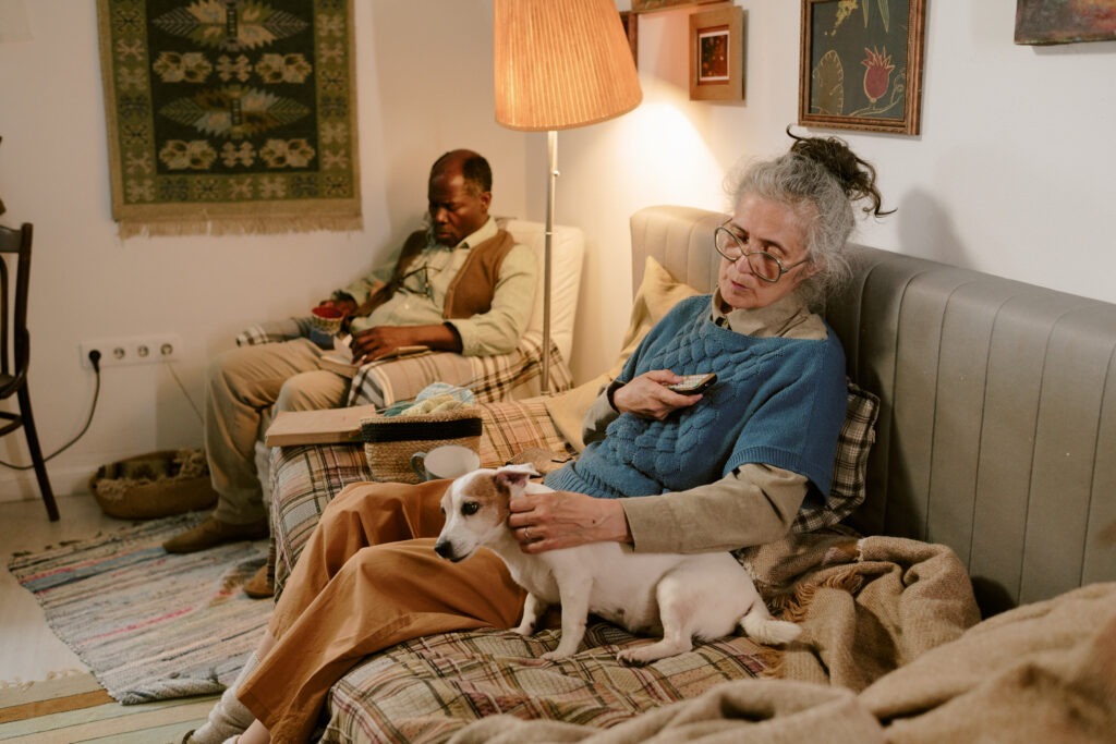 Casal idoso relaxado em casa com cão, ambiente doméstico e acolhedor, luz quente.