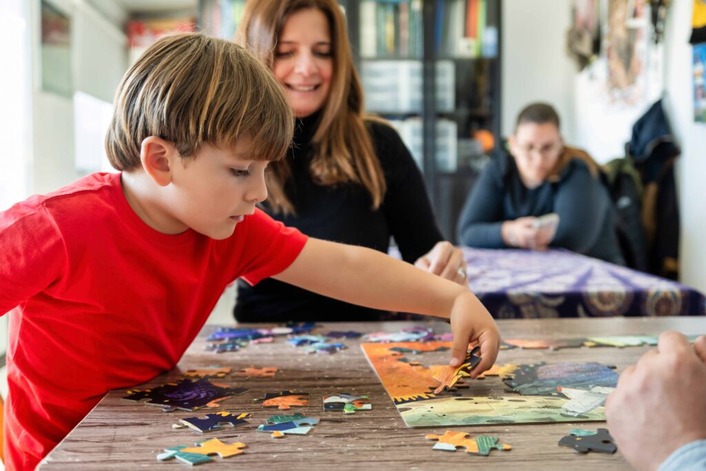 Adulto e criança a montar puzzle juntos no chão, momento de atenção e cumplicidade